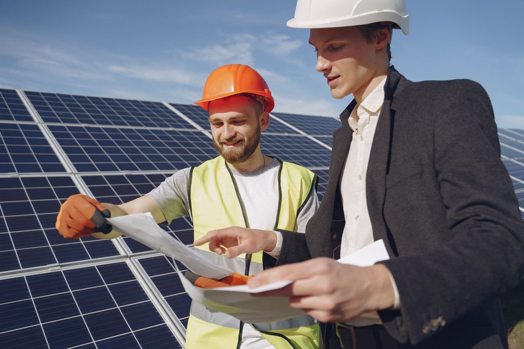 Due professionisti esaminano documenti di progetto accanto a pannelli fotovoltaici